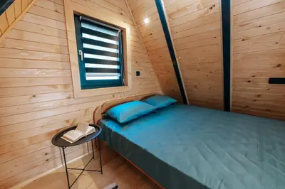 a small bed in a wooden cabin with a window at Lake House Beliz in Livno