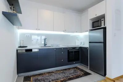 a kitchen with white cabinets and a black refrigerator at Sara Apartments in Visoko