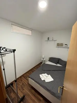 a small bedroom with a bed and a window at Apartman Harmani in Bihać