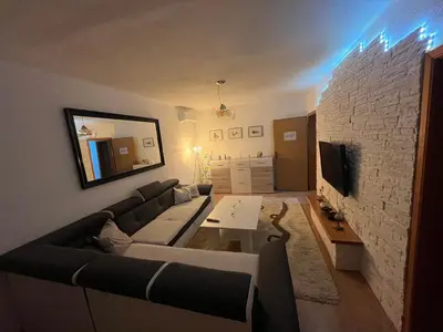 a living room with a couch and a stone wall at Apartman Harmani in Bihać