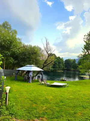 a group of chairs and an umbrella next to a lake at Unique Una in Ripač