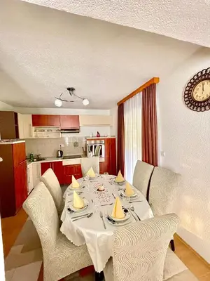 a dining room table with chairs and a kitchen at Unique Una in Ripač