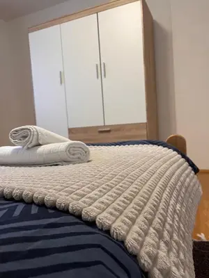 a bed with a blue and white blanket on it at Vito apartments in Jajce
